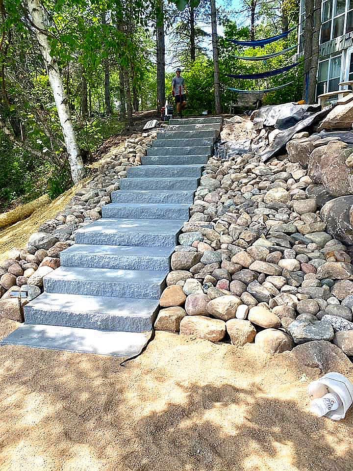rip rap slope with gray granite steps leading down to the backyard of a beach home