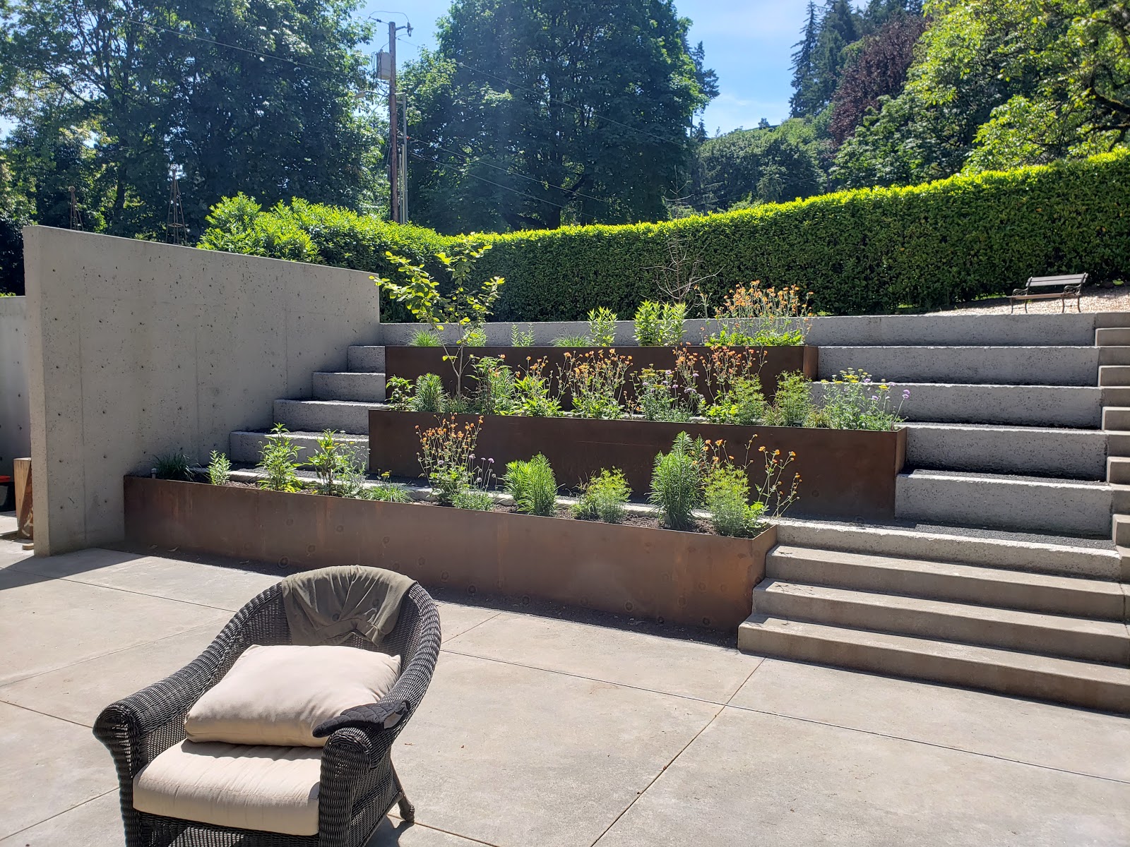 what is a retaining wall shown in upscale backyard with three rusty corten steel retaining wall holding back small green plants